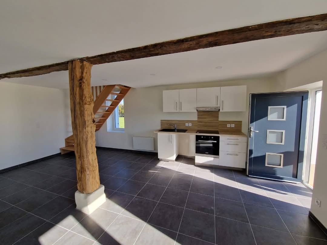 Cuisine ouverte avec carrelage gris, poutre bois apparente et porte d'entrée bleue