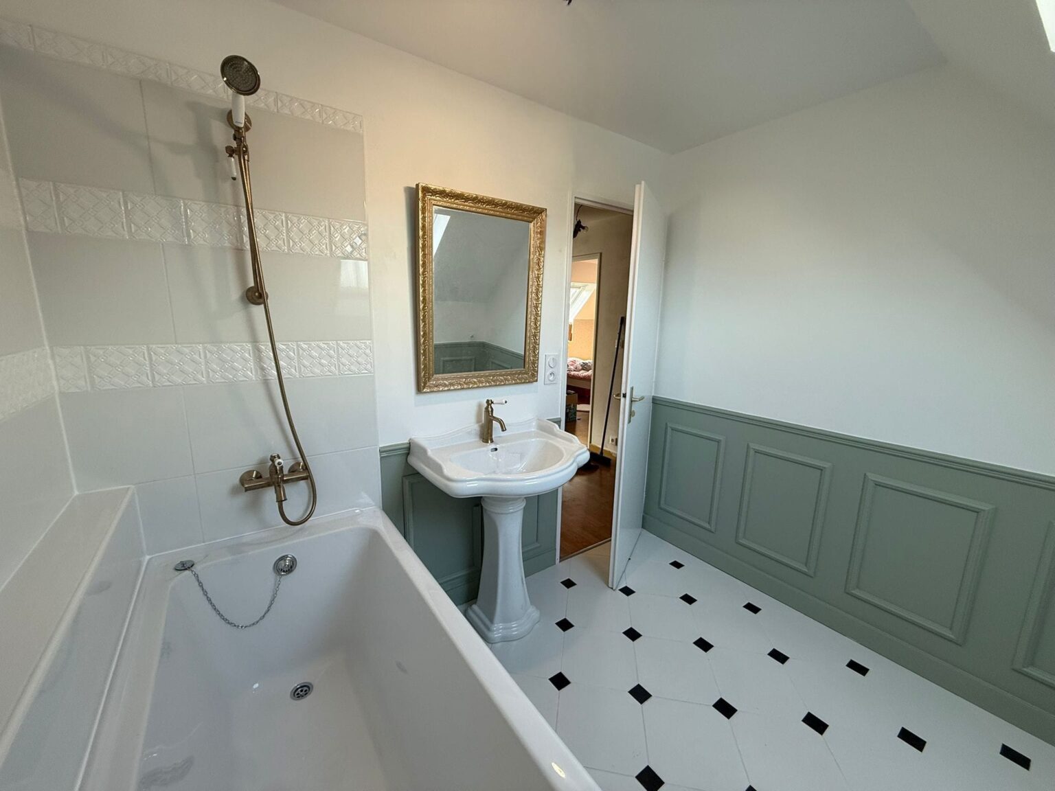 Salle de bain rénovée avec baignoire, lavabo sur pied et décoration verte et blanche