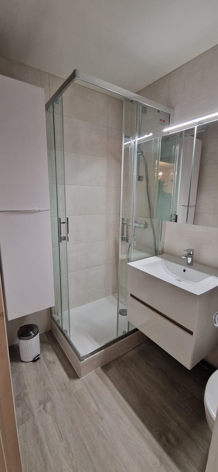 Salle de bain moderne avec cabine de douche en verre, lavabo suspendu et lame PVC