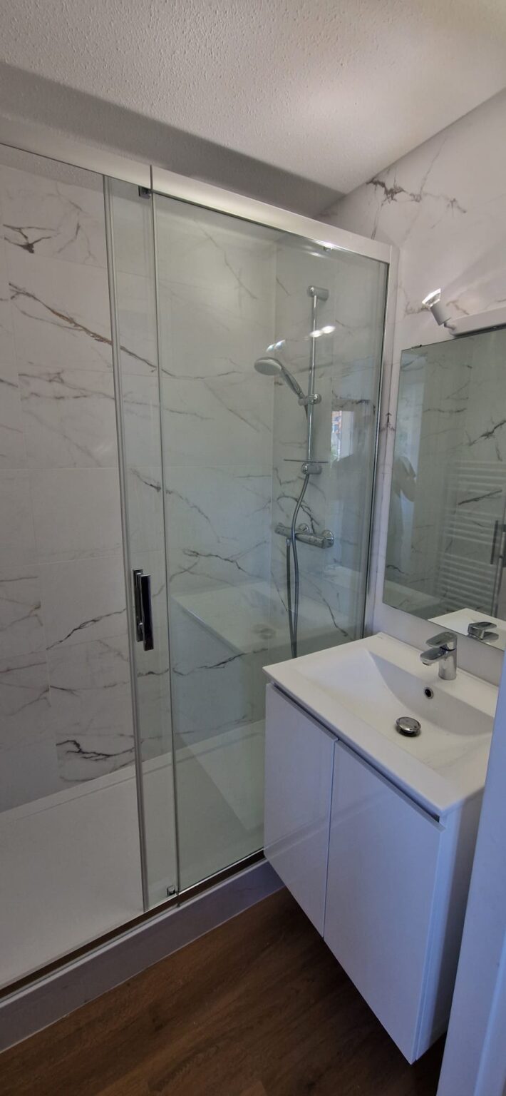 Salle de bain moderne avec douche italienne en verre et meuble vasque blanc