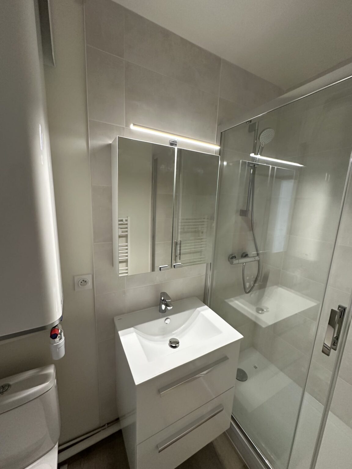 Salle de bain moderne avec meuble vasque blanc, miroir LED et cabine douche verre